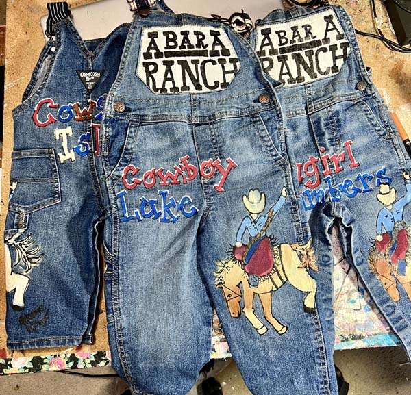 three pair of painted childrens overalls in a western design