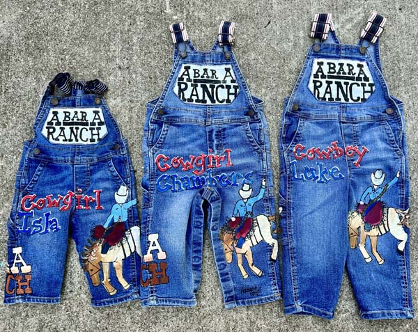 three painted overalls with red, white and blue painted cowboy design 